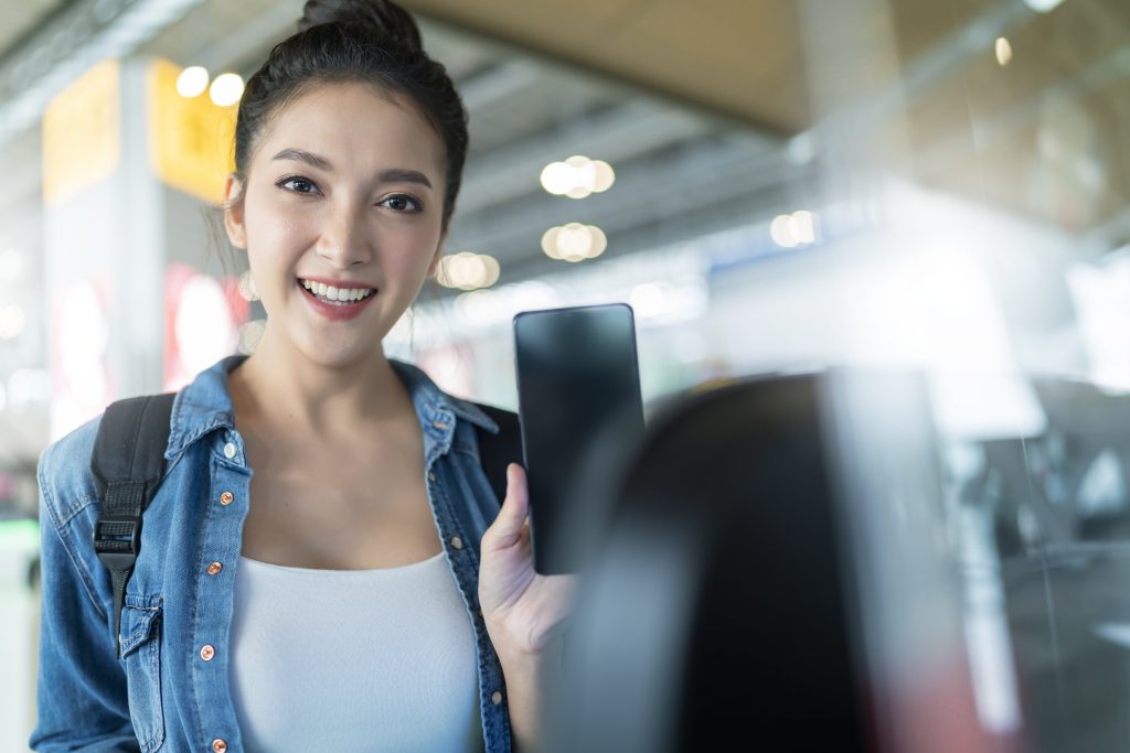 空港で携帯で乗車券を提示する若い女性