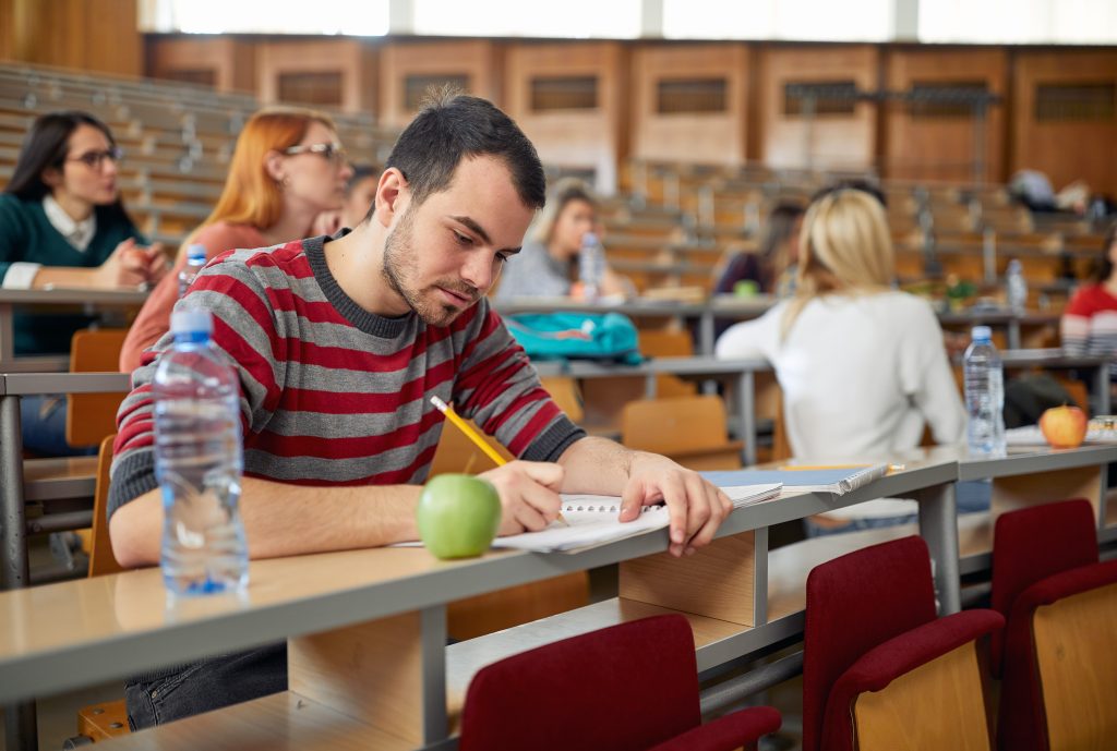 大学の講義で一心不乱にノートを取る学生