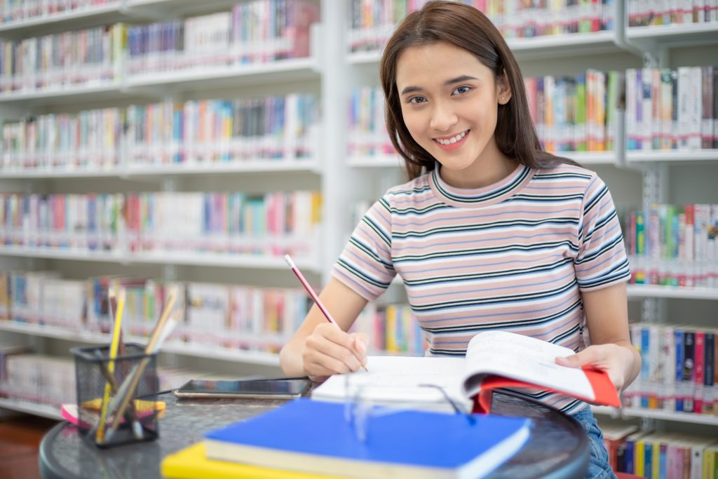 図書館で宿題と取り組む若い女子学生